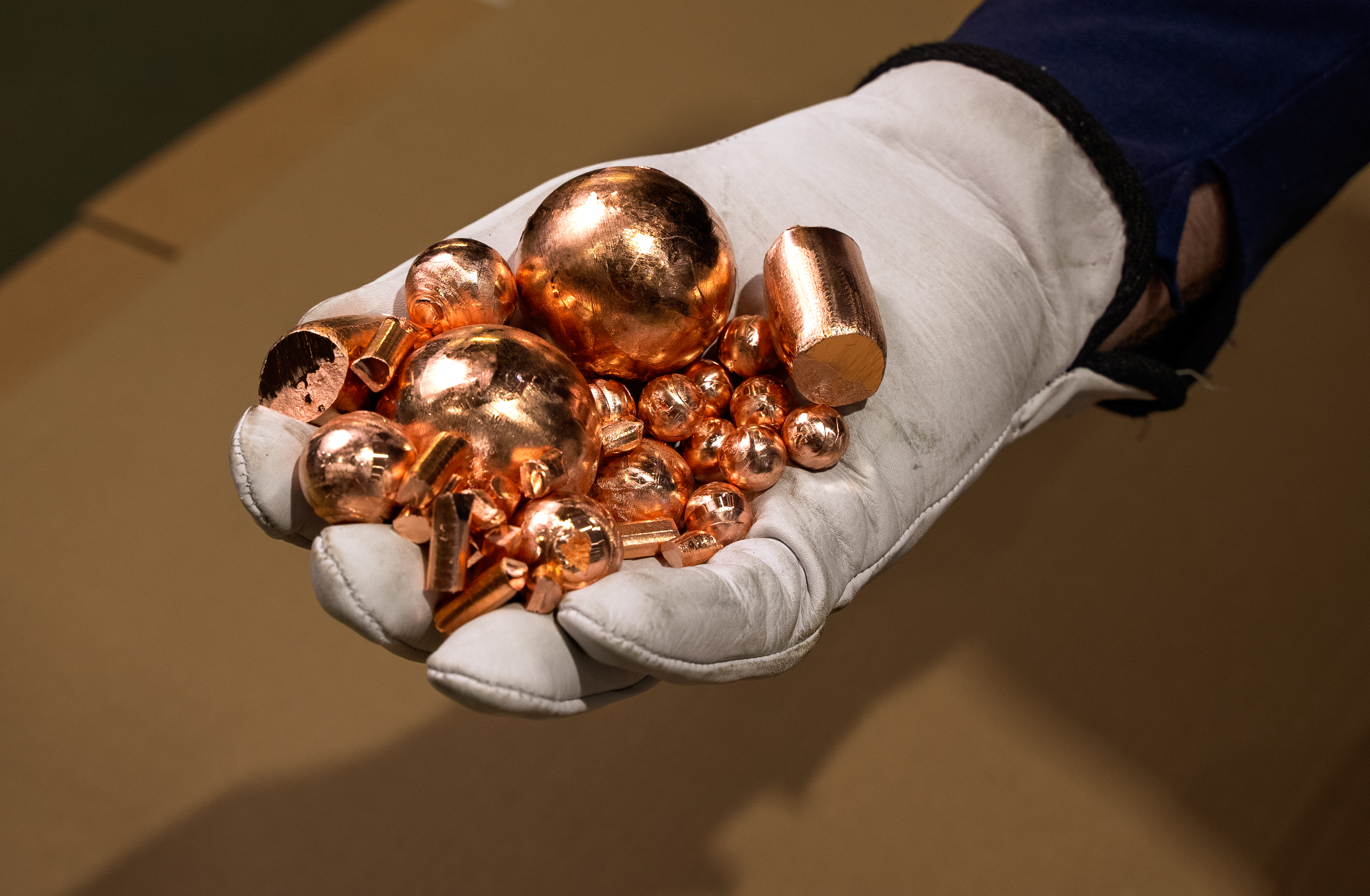 A hand holding different shaped and sized copper anodes for electroplating.