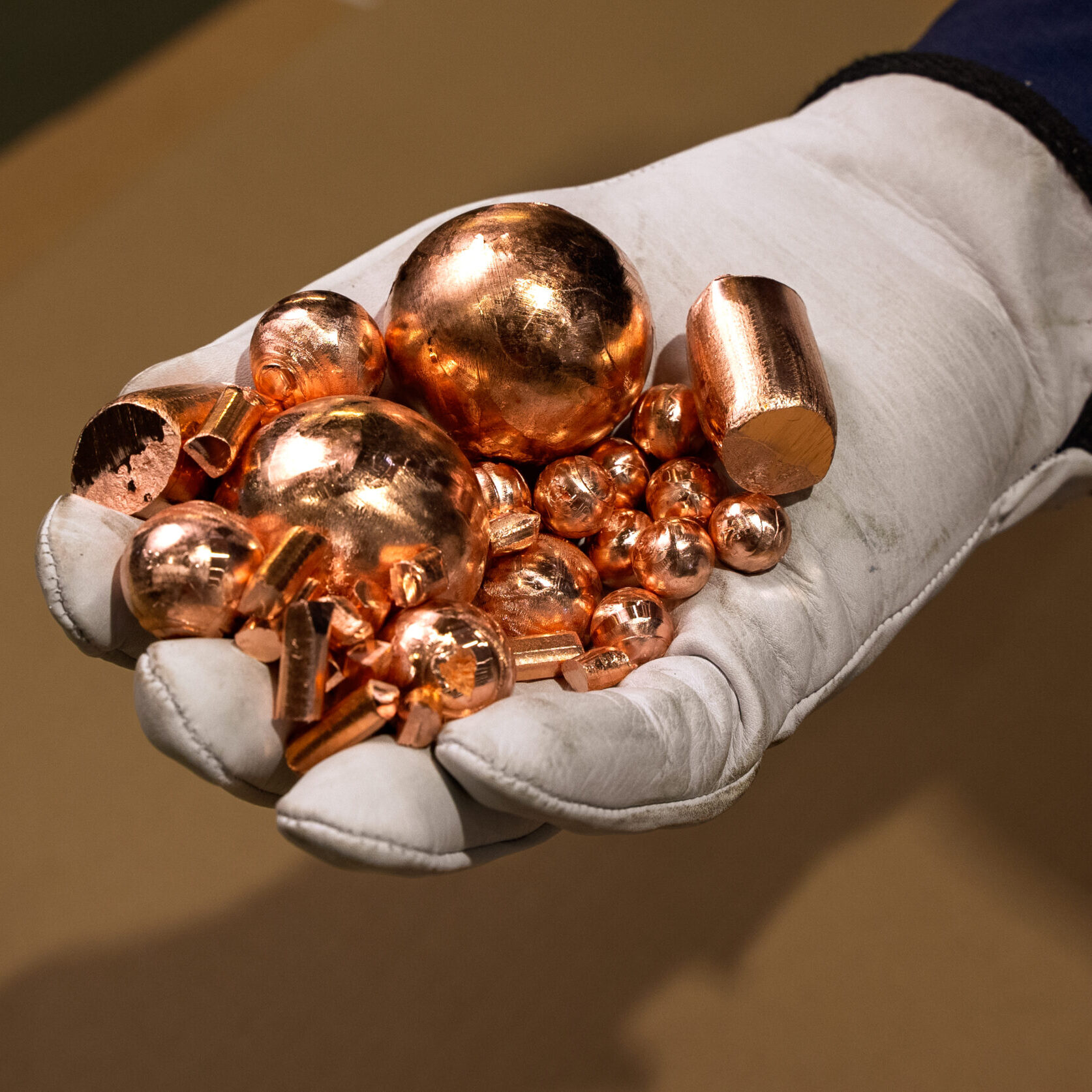 A hand holding different shaped and sized copper anodes for electroplating.